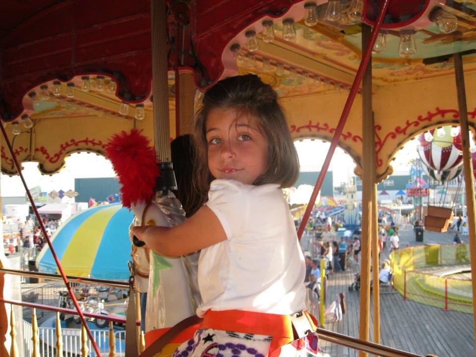 young Jessi Walker clinging to a merry-go-round horse